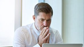 Man with his hands together on his laptop