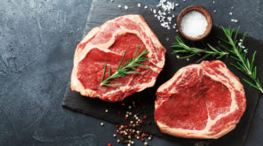 Fresh meat on slate black board top view. Raw beef steak and spices for cooking.